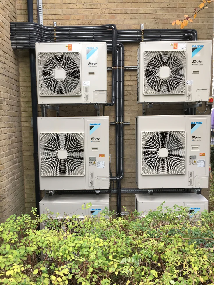 Multiple outdoor air conditioning units with grouped insulated pipework.