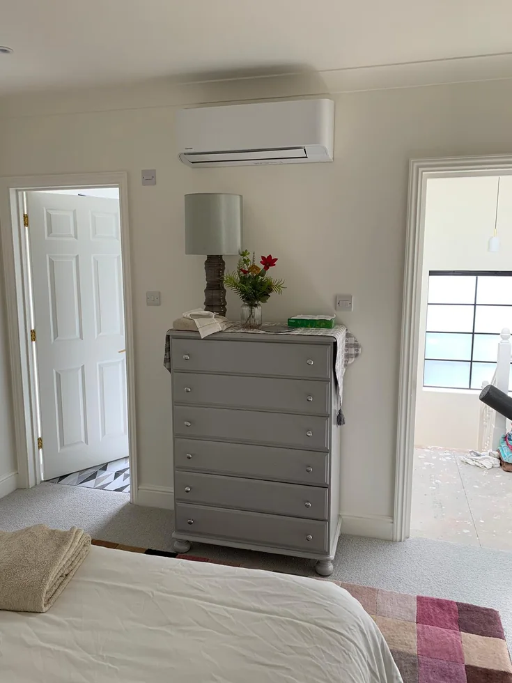 A wall-mounted unit above a chest of drawers in a bedroom.