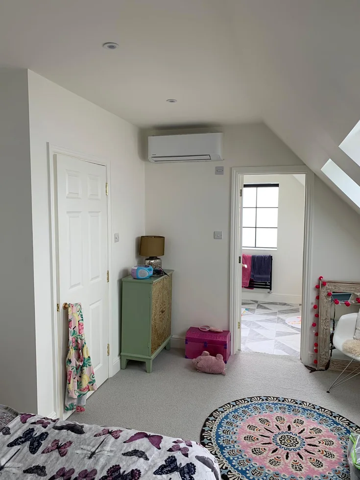 Wall-mounted air conditioning in a bedroom beneath a sloping ceiling.